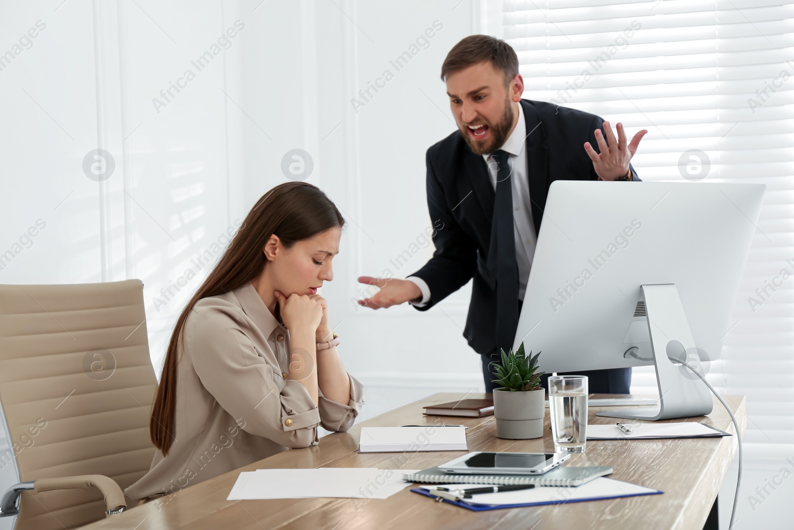 Photo of Boss screaming at employee in office. Toxic work environment