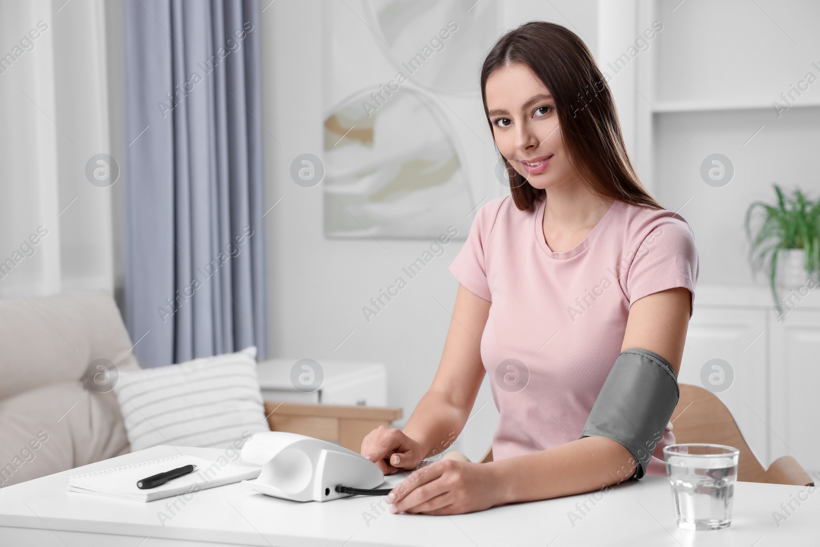 Photo of Woman measuring blood pressure with tonometer at home