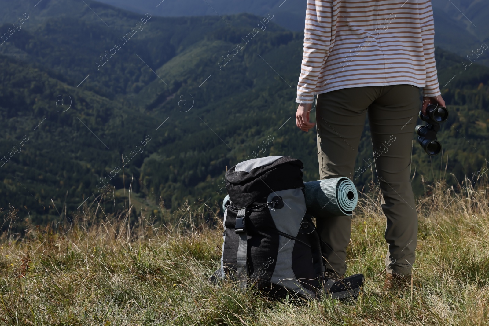 Photo of Back view of tourist with hiking equipment and binoculars in mountains, closeup