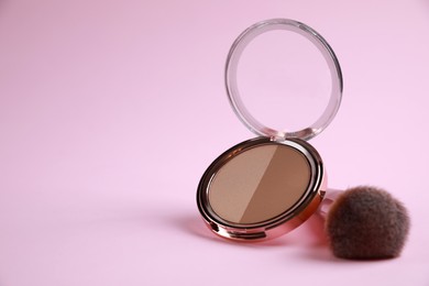 Face powder and brush on pink background, space for text