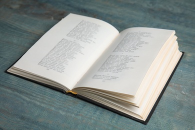 Photo of Open book on light blue wooden table