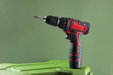 Photo of Modern electric screwdriver and case on pale green background