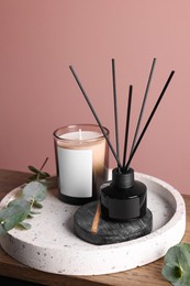 Photo of Composition with aromatic reed air freshener on wooden table near pink wall