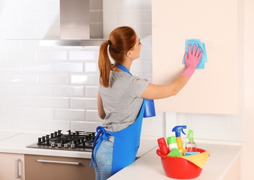 Woman cleaning kitchen with rag, indoors