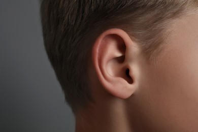 Photo of Boy on grey background, closeup of ear