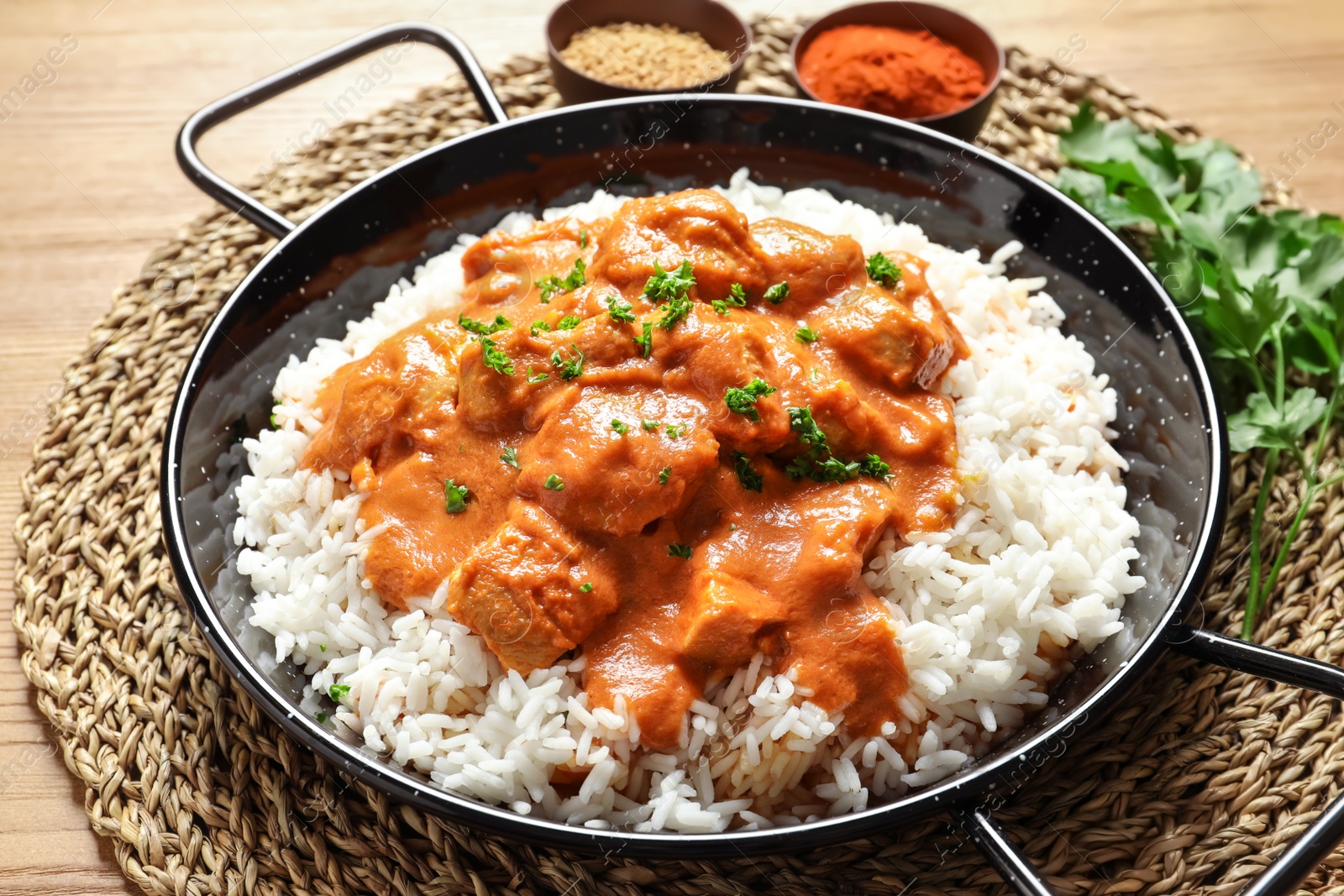 Photo of Delicious butter chicken with rice in dish on wooden table