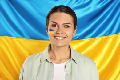 Young woman with face paint near Ukrainian flag