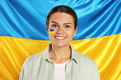 Photo of Young woman with face paint near Ukrainian flag