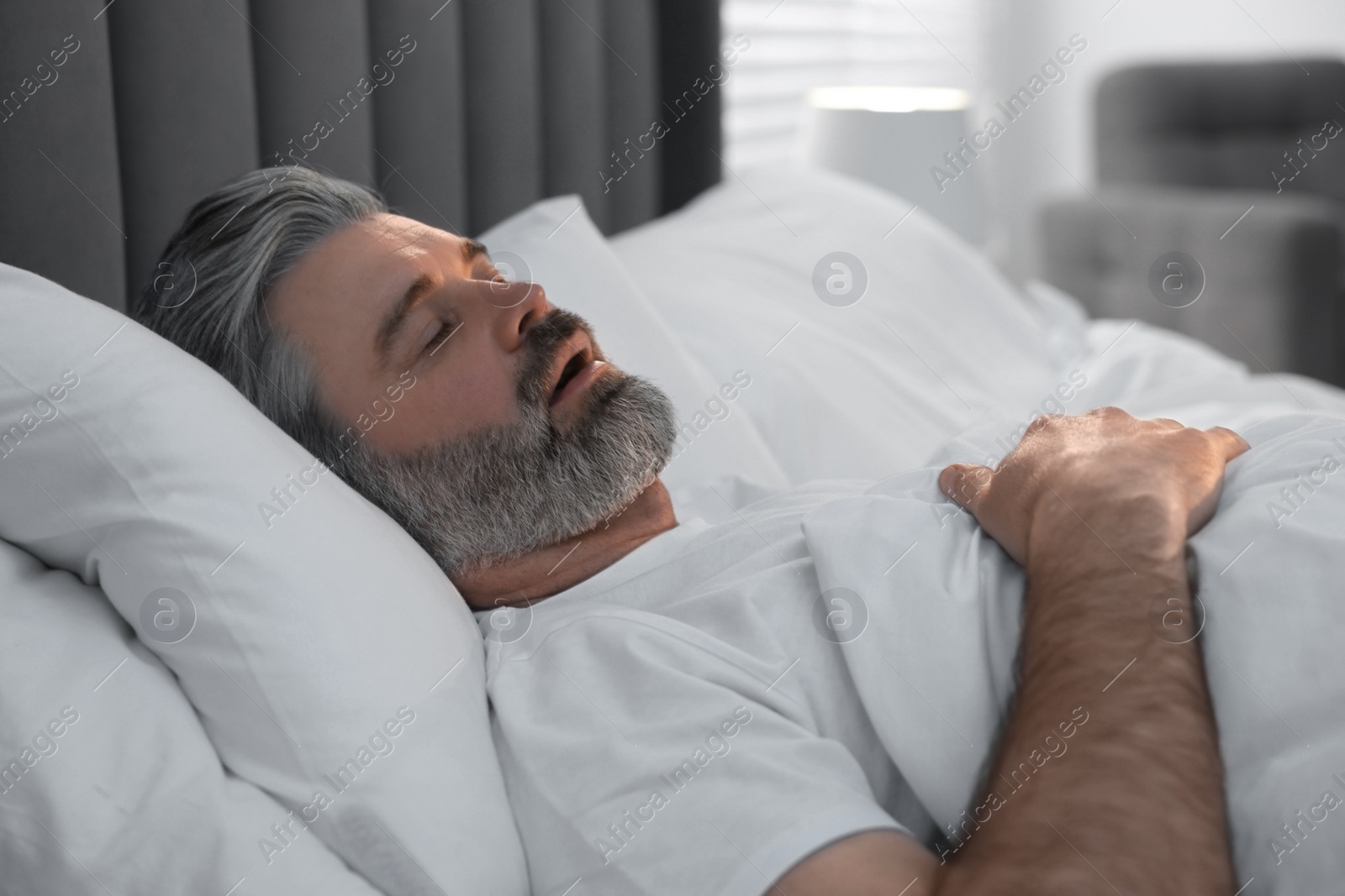 Photo of Man snoring while sleeping in bed at home