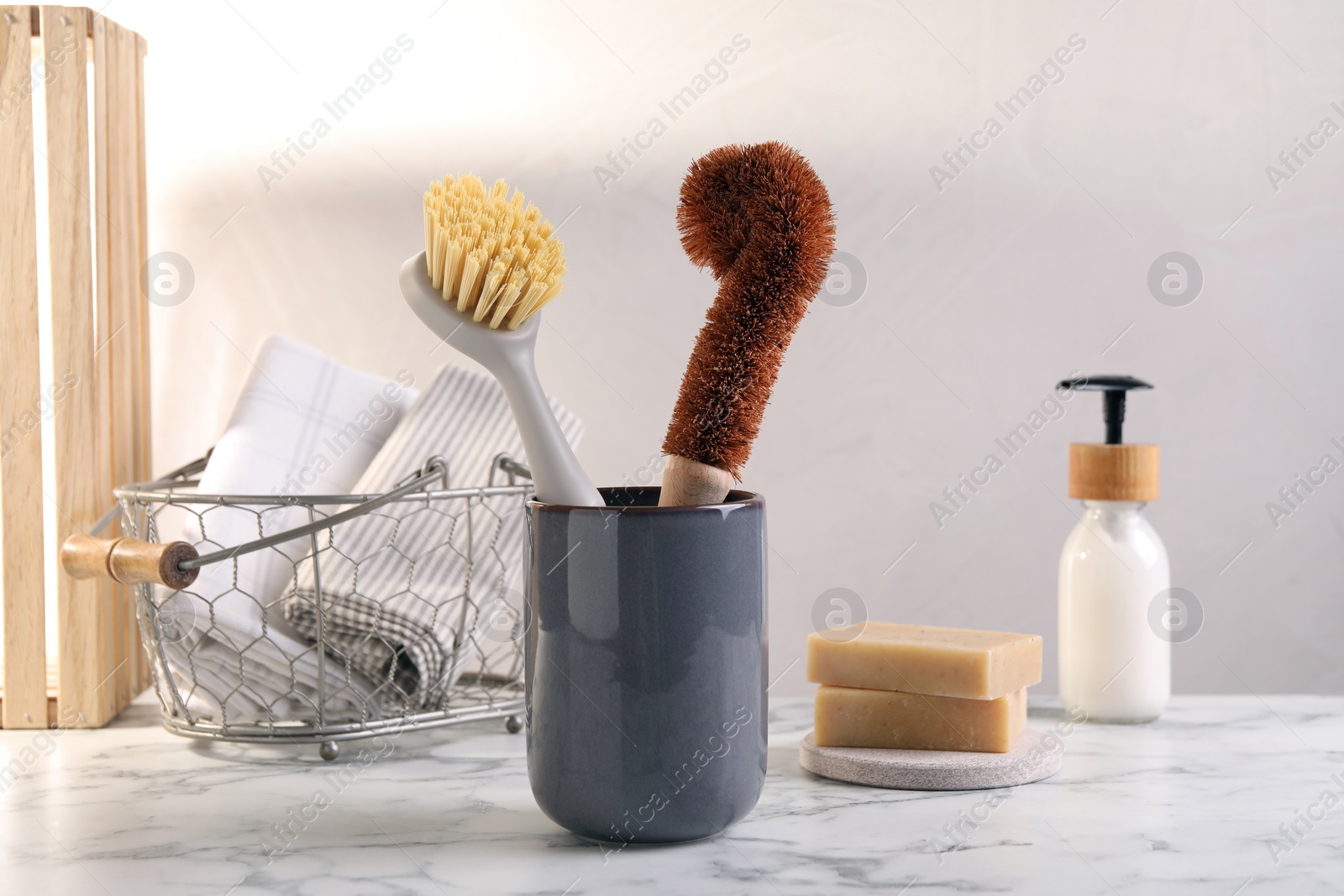 Photo of Brushes in holder and cleaning tools on white marble table