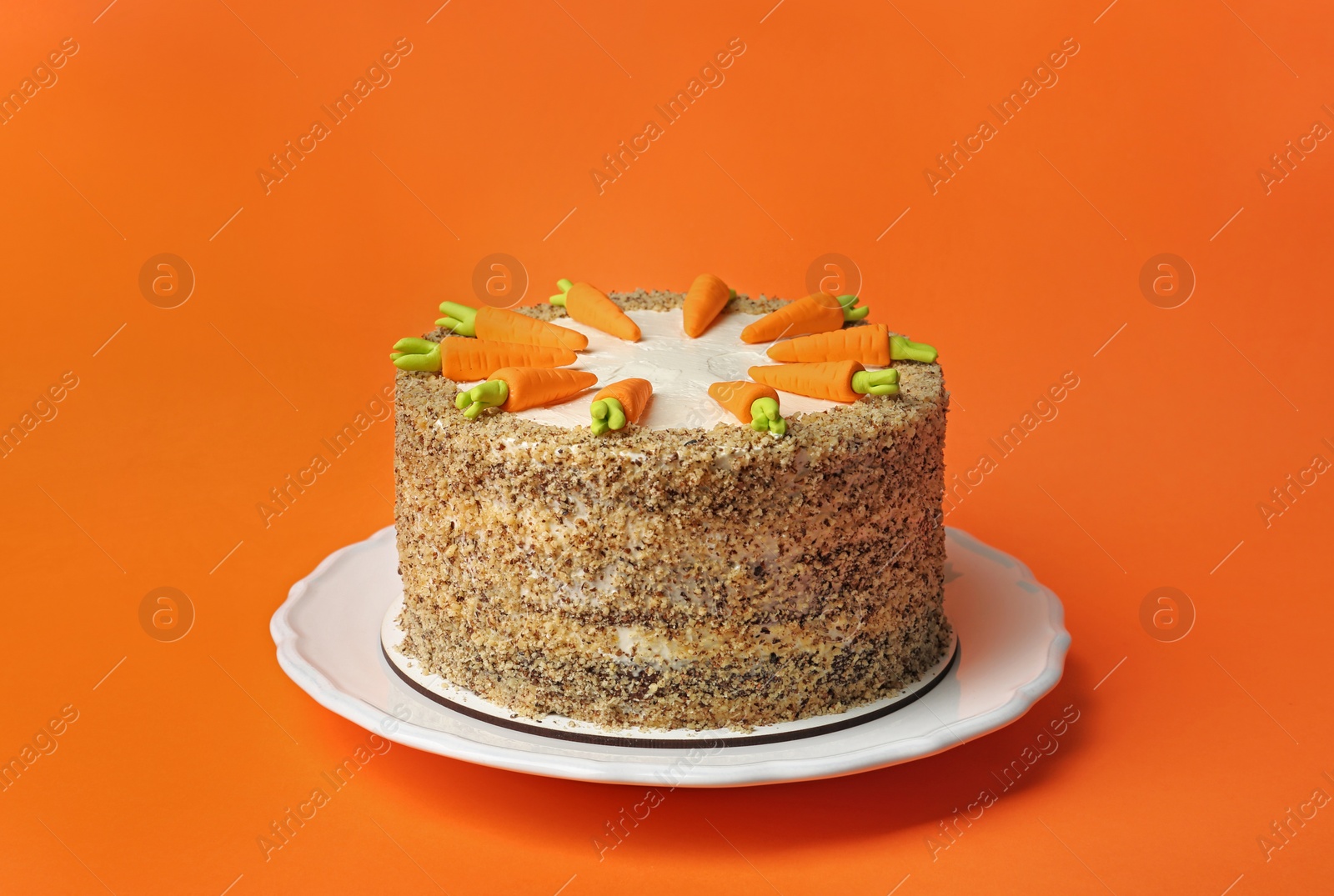 Photo of Dish with tasty carrot cake on orange background