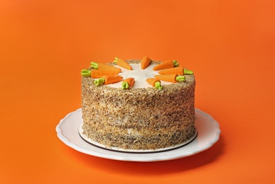 Dish with tasty carrot cake on orange background