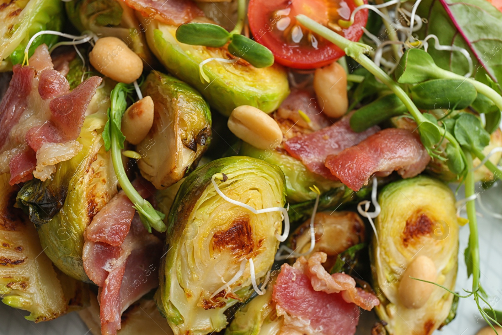 Photo of Delicious roasted Brussels sprouts with bacon on plate, top view