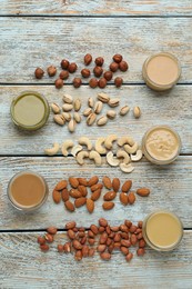 Different types of delicious nut butters and ingredients on light blue wooden table, flat lay