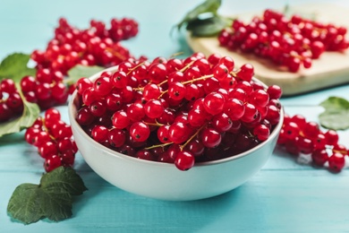 Photo of Delicious red currants on light blue wooden table