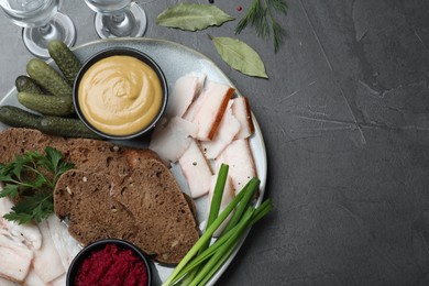 Tasty salt pork with rye bread and sauces served on grey table, flat lay. Space for text