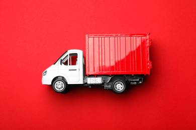 Top view of toy truck on red background, space for text. Logistics and wholesale concept
