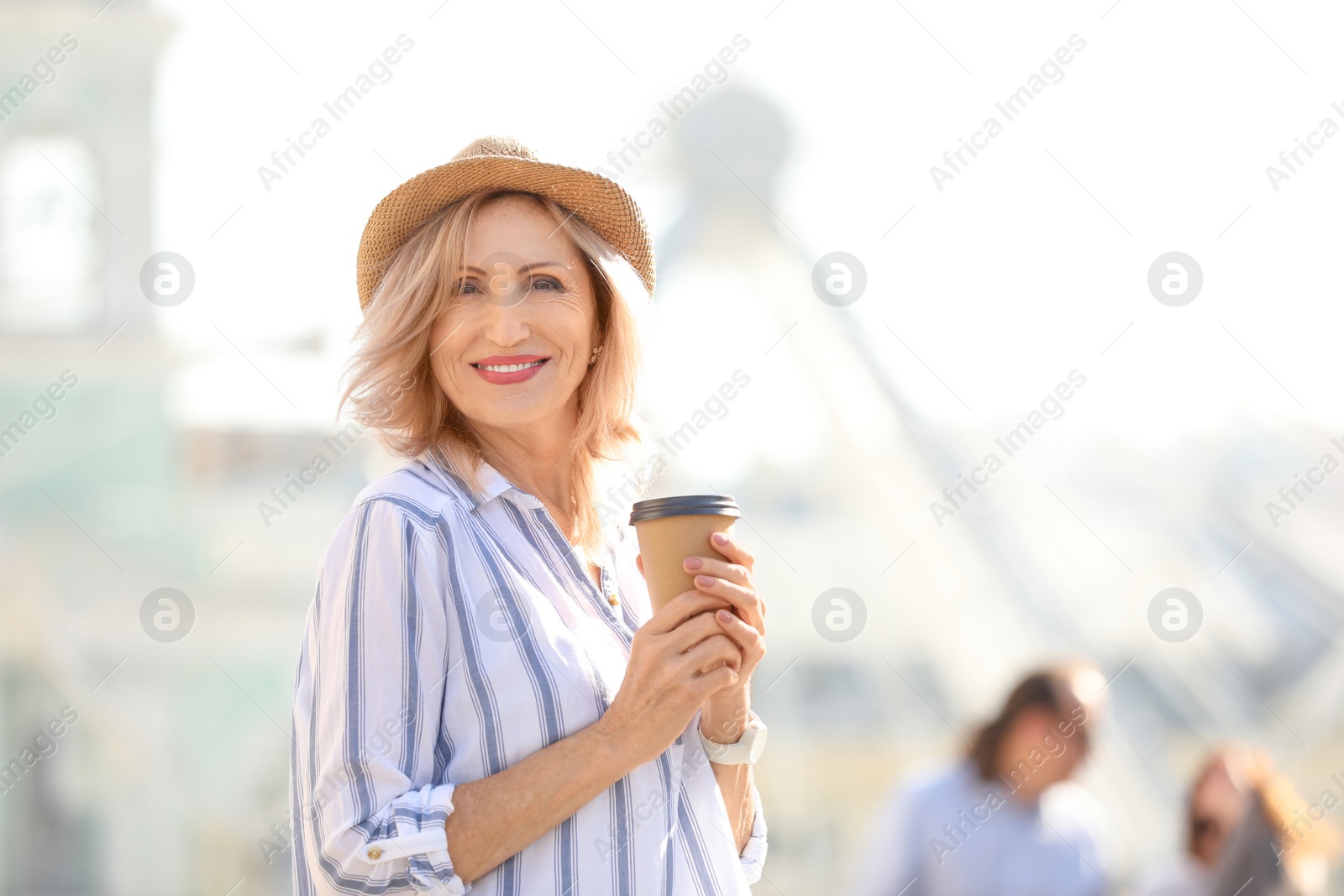 Photo of Beautiful mature woman with cup of coffee outdoors