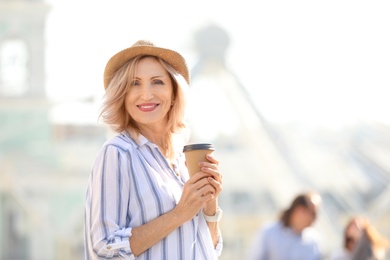 Photo of Beautiful mature woman with cup of coffee outdoors