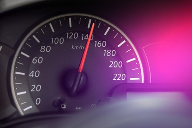Speedometer on car dashboard under pink light, closeup