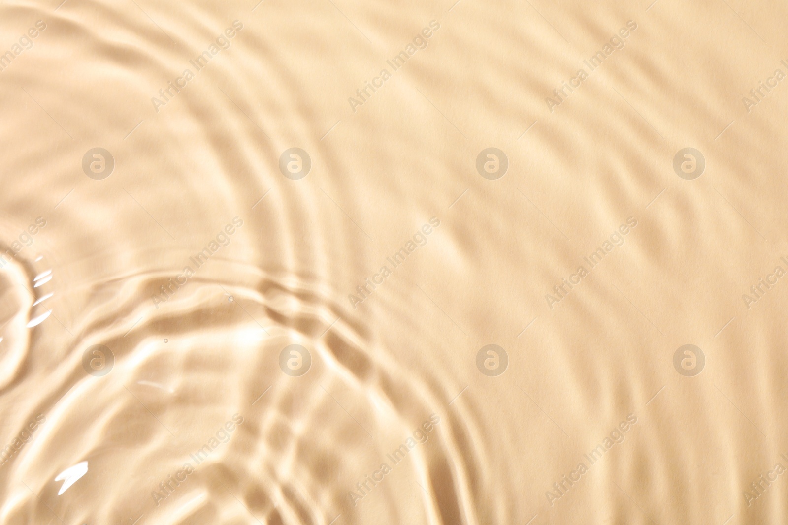 Photo of Closeup view of water with rippled surface on beige background