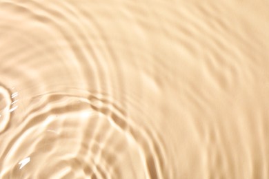 Photo of Closeup view of water with rippled surface on beige background