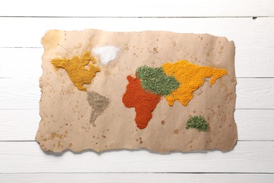 Photo of World map of different spices on white wooden table, top view