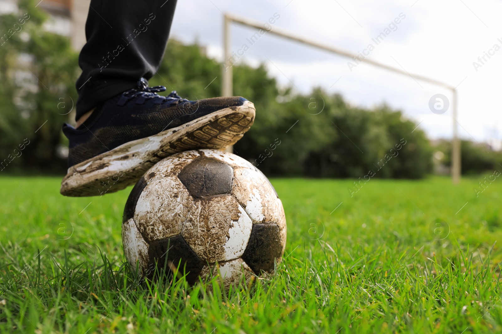 Photo of Man with dirty soccer ball on green grass outdoors, closeup. Space for text