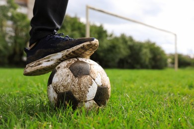 Photo of Man with dirty soccer ball on green grass outdoors, closeup. Space for text