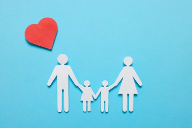 Photo of Paper family figures and red heart on light blue background, flat lay. Insurance concept