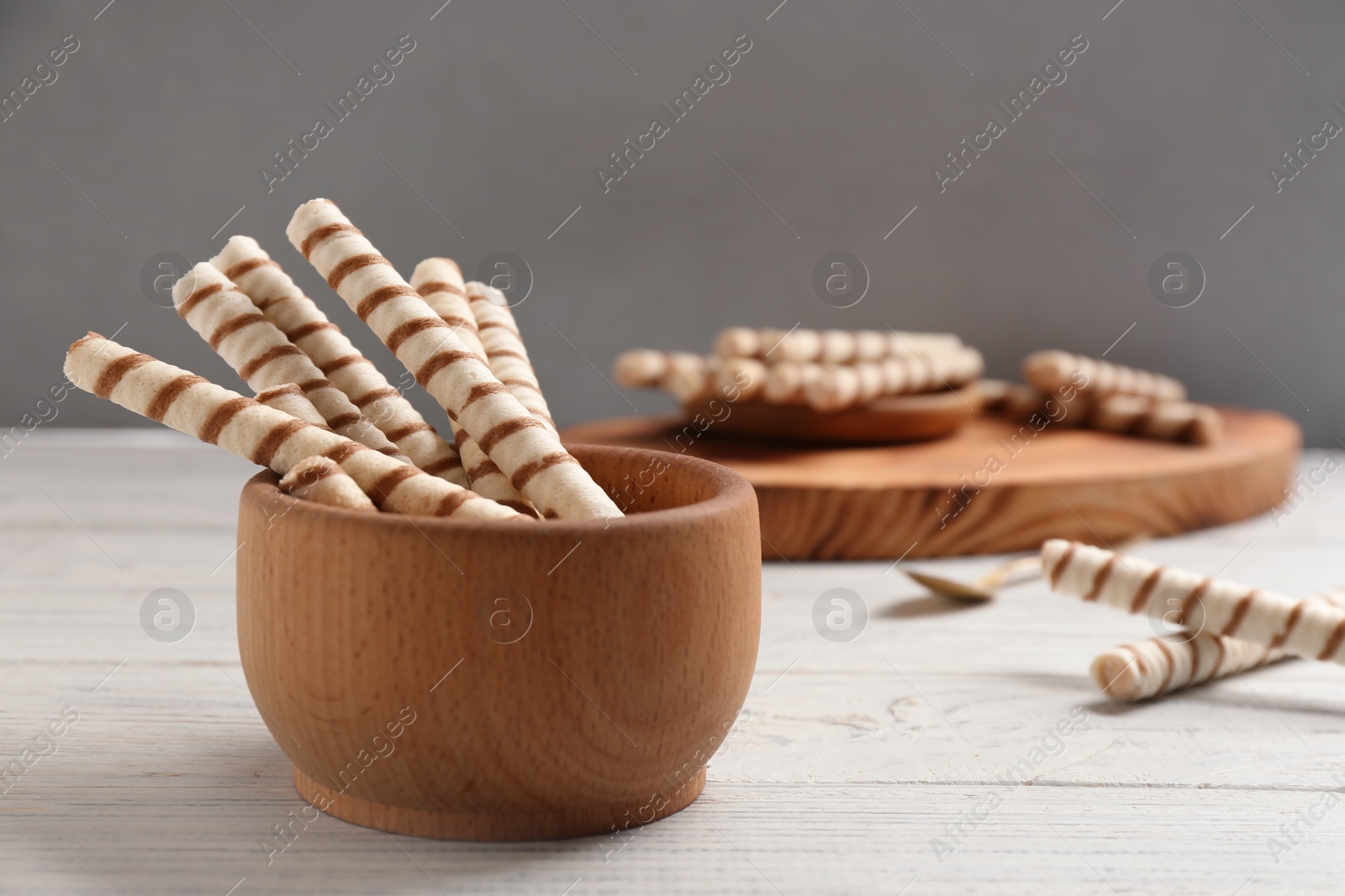 Photo of Bowl with delicious wafer rolls on white wooden table. Sweet food