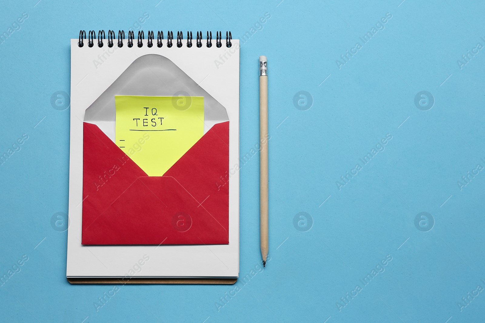 Photo of Note with words IQ Test in envelope, notebook and pencil on light blue background, flat lay. Space for text
