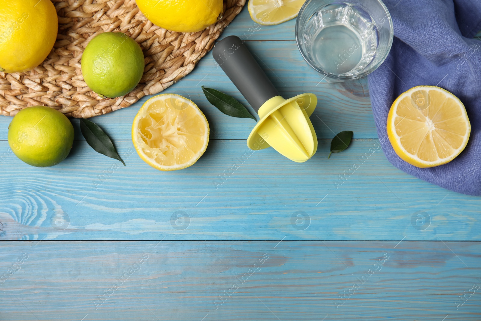 Photo of Citrus reamer, fresh lemons and limes on light blue wooden table, flat lay. Space for text