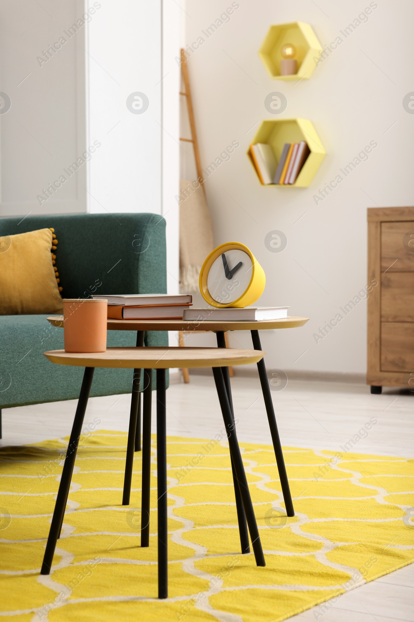 Photo of Spring interior. Yellow clock, books and candle on wooden table in living room