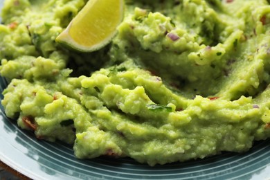 Delicious guacamole with lime on plate, closeup