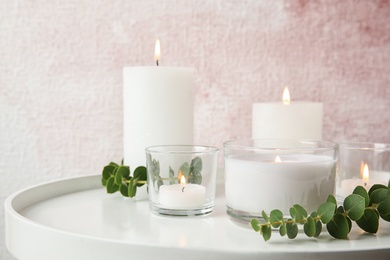 Composition with burning aromatic candles and eucalyptus on table. Space for text