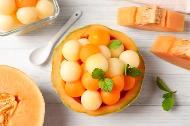 Different melon balls with mint on white wooden table, flat lay