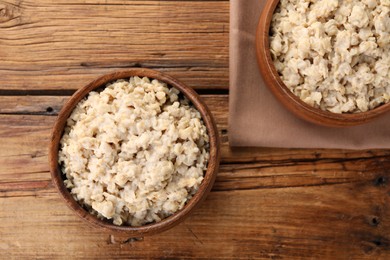 Photo of Tasty boiled oatmeal on wooden table, flat lay