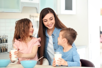 Photo of Happy family having breakfast with milk in kitchen