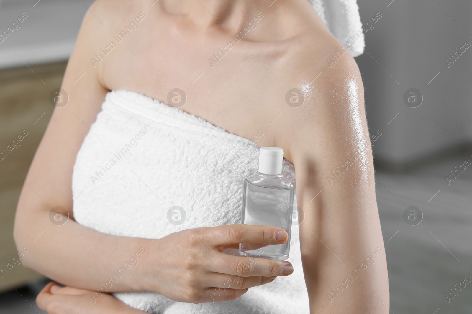 Photo of Woman with bottle of body oil on blurred background, closeup