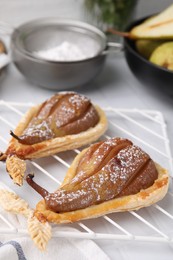 Photo of Delicious pears baked in puff pastry with powdered sugar on table, closeup