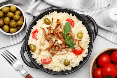 Photo of Tasty couscous with mushrooms, olives and tomatoes served on grey table, flat lay