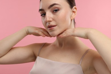 Photo of Beautiful woman touching her chin on pink background, closeup