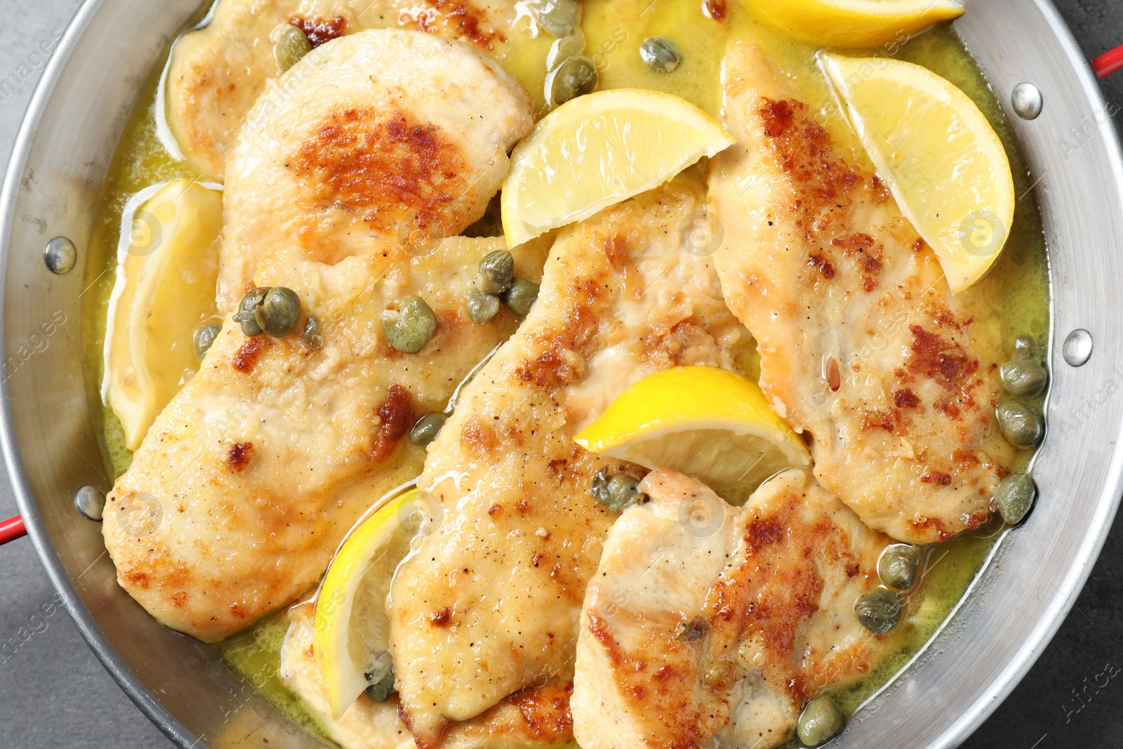 Photo of Delicious chicken piccata with lemons in pot, top view