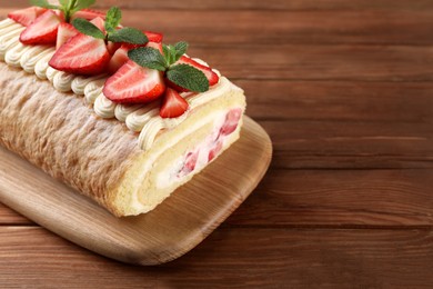 Delicious cake roll with strawberries and cream on wooden table. Space for text