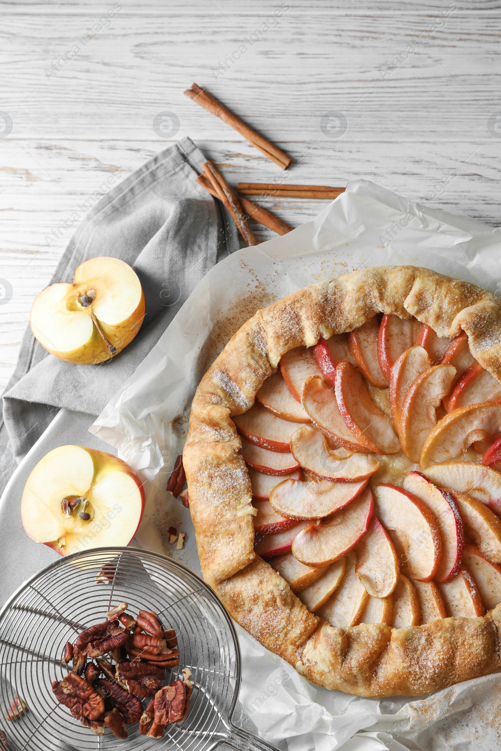 Photo of Delicious apple galette, cinnamon and pecans on table, flat lay