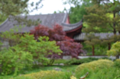 Photo of Blurred view of oriental building among trees in park