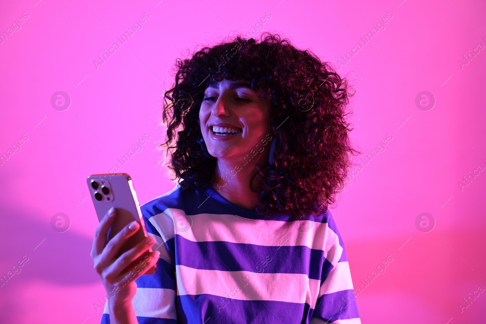 Photo of Beautiful young woman taking selfie on color background in neon lights