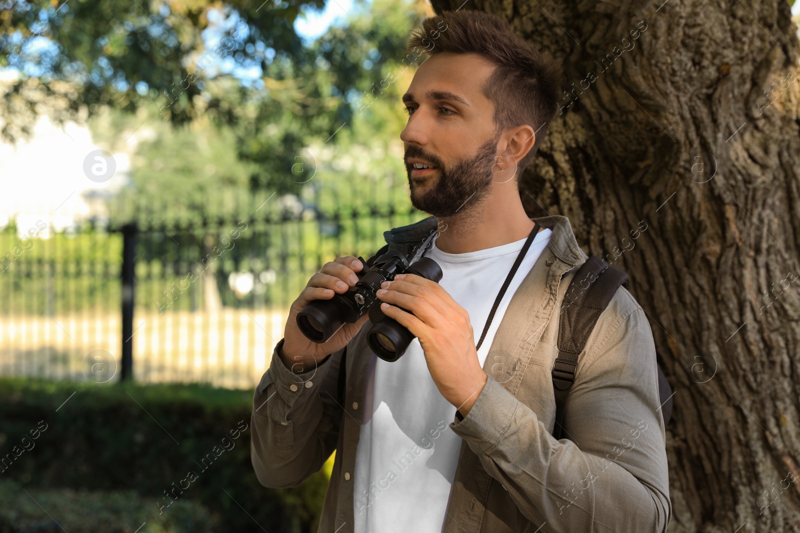 Photo of Handsome man with binoculars spending time in nature reserve