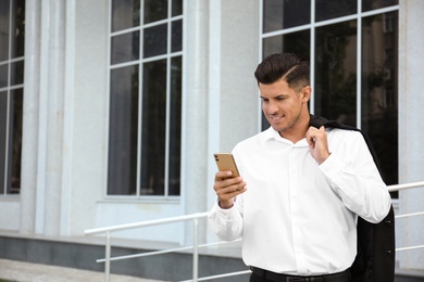 Photo of Handsome man with smartphone on city street